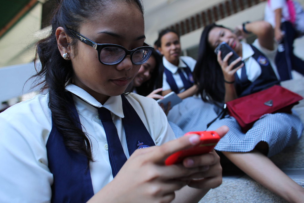 A student at St. Francis of Assisi School, and other girls, check their smart phones after classes in the Central Visayas city of Cebu, Philippines. Photo: UNICEF/Estey